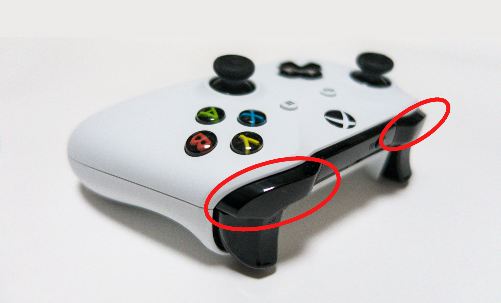 white xbox one controller with red circles draw around the shoulder buttons